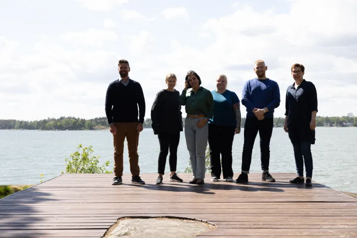 Folk som står nede ved sjøen på en brygge på rekke og rad 